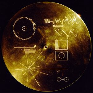 La copertina del disco ricoperto d’oro, del diametro di 12 pollici (30,5 cm.) che si trova all’interno delle sonde Voyager. Le immagini rappresentano con le istruzioni di utilizzo del disco, qualora siano ricevute da un’entità intelligente. Il disco all’interno riproduce saluti in 60 lingue, musiche etniche e vari suoni. NASA/JPL, Pubblico Dominio